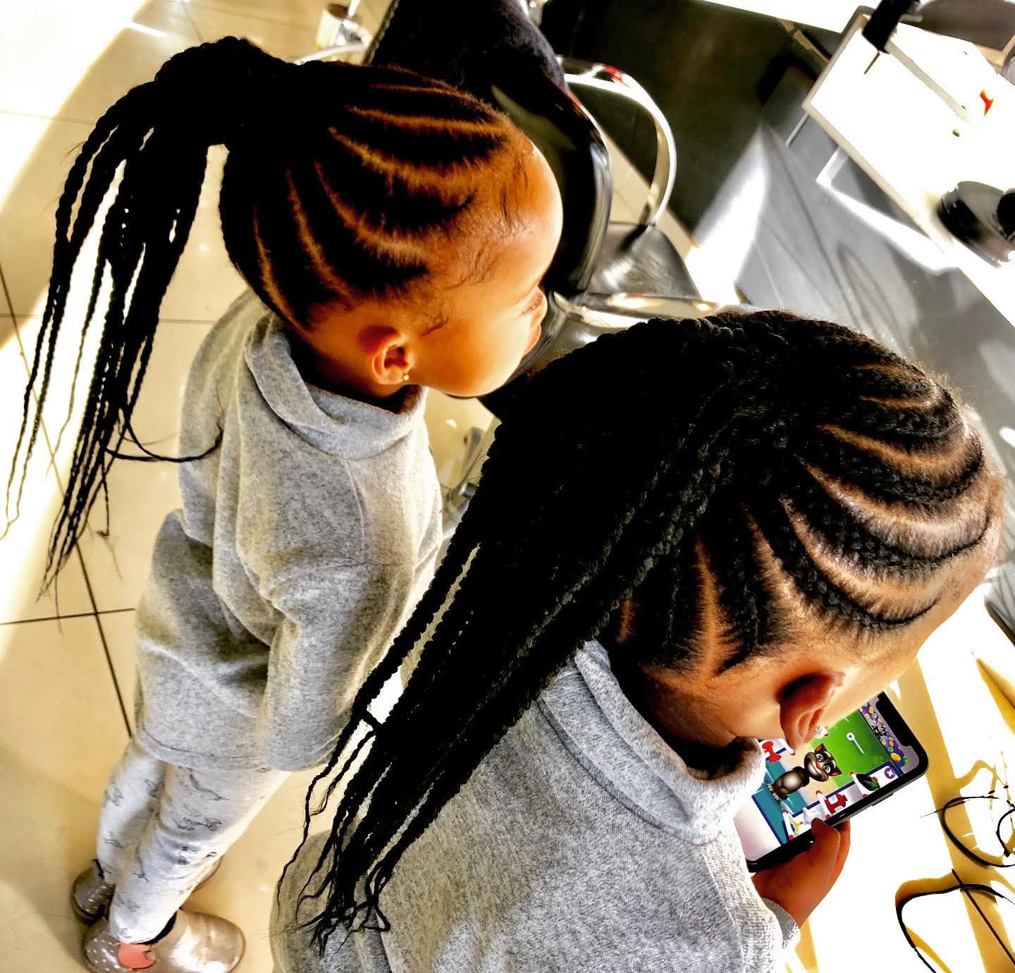 Neat cornrow ponytails on two young girls at the salon